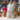Fluffy Inkari Stuffed Alpaca in store display with colorful yarn background