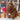 Natural Inkari Stuffed Alpaca Animal in a store display, showcasing its fluffy brown fur and soft texture amid colorful yarns.