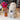 Inkari Stuffed Alpaca next to a vase with dried flowers, surrounded by colorful yarn balls in a cozy shop setting