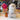 Inkari Stuffed Alpaca Animal in white, fluffy texture, displayed on a table next to a vase of flowers.