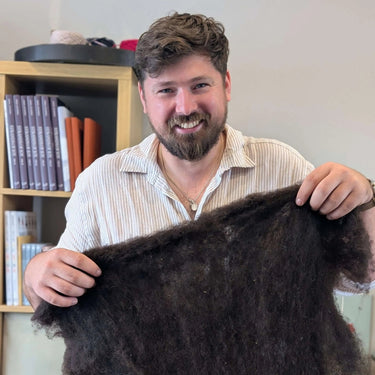 Matthew holding wool fleece during Yarn Spinning class workshop.