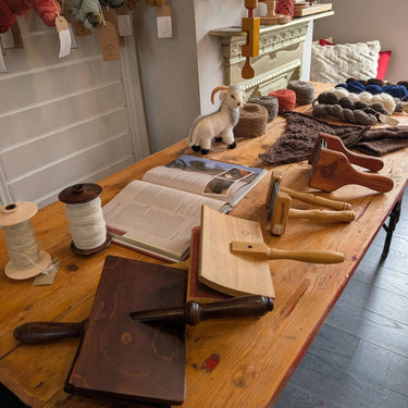 Workshop table setup for a Yarn Spinning class with tools, yarn, and fleece.