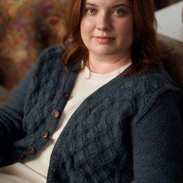 Woman wearing a blue knitted cardigan with a blurred background