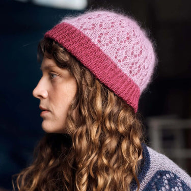 Woman wearing a pink knitted hat and blue sweater against a blurred background