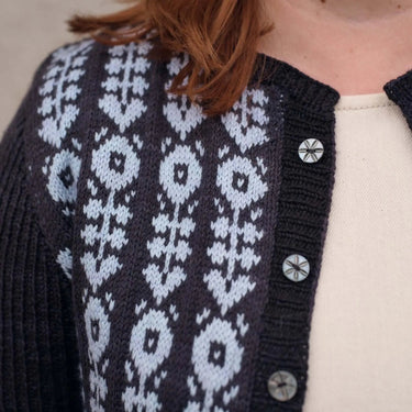 Navy blue cardigan with white geometric pattern worn by a person