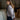 Woman in a gray cardigan standing in a room with wooden beams.