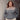 Person wearing a two-tone sweater standing against a concrete wall.