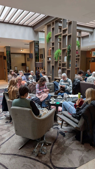 Knit social at Clayton Hotel, Chiswick with people knitting and chatting in a cozy setting.