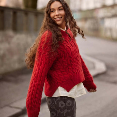 Person wearing a red sweater standing outdoors with blurred background