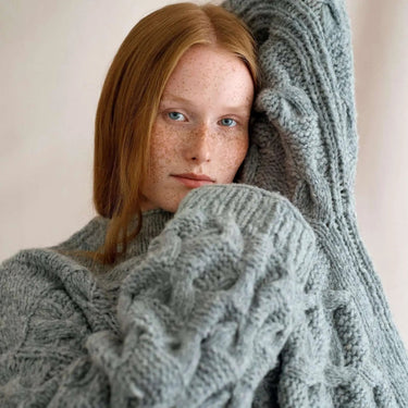 Model wearing a cozy cable knit sweater from Laine Magazine Issue 27 - Winter PRE-ORDER, showcasing winter knitting designs.