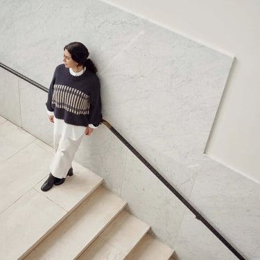 Model wearing knit sweater on stairs, featuring Laine Magazine Issue 27 design; pre-order the latest winter collection now.