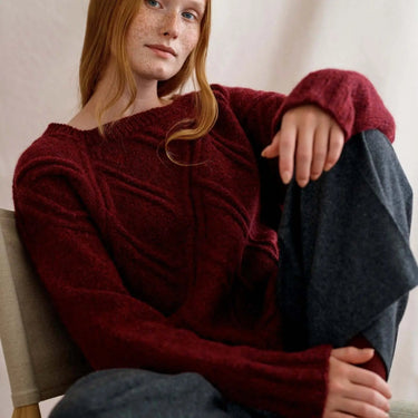 Model wearing design from Laine Magazine Issue 27 Winter PRE-ORDER, showcasing bold cables in red knitted sweater.