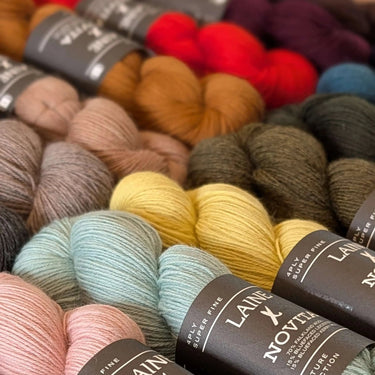 Assorted skeins of yarn with 'Laine Novia' labels in a close-up shot.