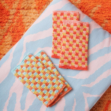Colorful crochet swatches on patterned fabric, showcasing designs from Let's Crochet Issue 2 by Laine, available for pre-order.