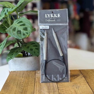 LYKKE brand knitting needles in packaging on a wooden table with a plant in the background at knit with me yarn shop