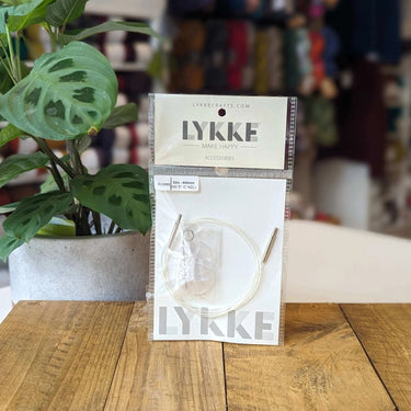 LYKKE Interchangeable Cords packaging on a wooden table with a plant in the background