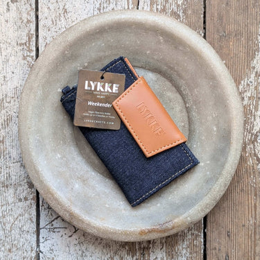 Lykke Weekender Knitting Needle Travel Case made of denim and vegan leather on a wooden surface.