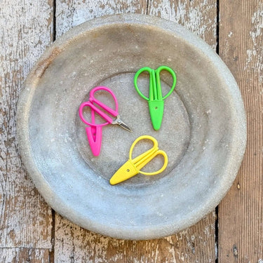 Colorful Mini Scissors with silicone guard in pink, green, and yellow on rustic plate, perfect for travel and on-the-go use.