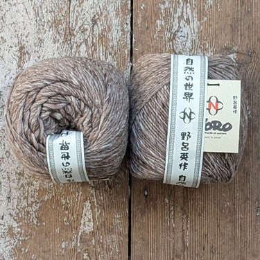 Noro Haunui natural merino wool yarn from New Zealand in 200g barrels on wooden background.