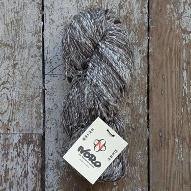 Noro Haunui Silk yarn blend of merino wool and raw mulberry silk on rustic wooden background.