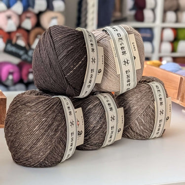 Three skeins of Noro Haunui natural merino wool yarn on display, undyed and unique in color, from Taranui farm in New Zealand.