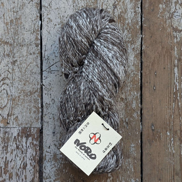 Noro Haunui Silk yarn blend of merino wool and raw mulberry silk on rustic wooden background.