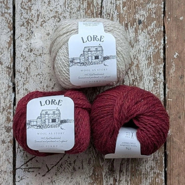 Three balls of Lore yarn on a wooden surface, featured in Knitting Kit.