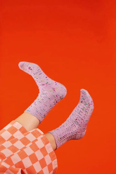 Colorful knitted socks from Ready Set Socks Knitting Book against orange background