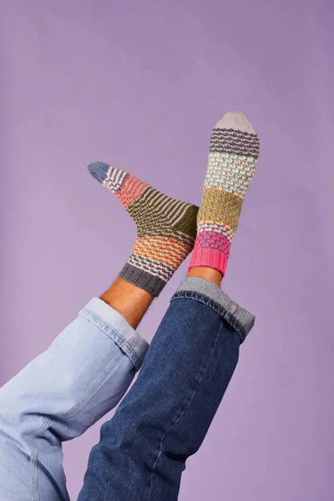 Colorful socks from Ready Steady Sock Knitting Book displayed on crossed legs.
