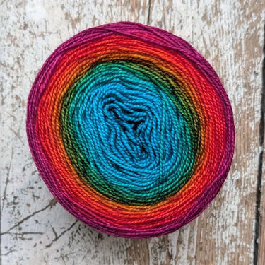 Snek by Bilum gradient hand-dyed merino wool yarn in vibrant colors on rustic wood surface.