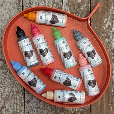 Sock Stop non-slip sole creator bottles on a red tray for homemade socks and booties.