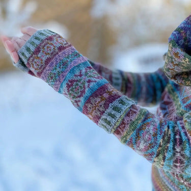 Colorful knitted Sycamore Armwarmers Kit by Marie Wallin on a snowy background, showcasing detailed patterns in wool yarn.