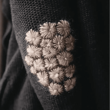 The Art of Knitwear Repair book cover showing intricate mending on a dark fabric patch.