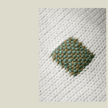 The Art of Knitwear Repair - Close-up of a repaired knit sweater showing intricate darning stitches.