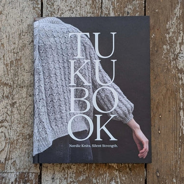 Cover of Tukubook highlighting Nordic knits with a textured sweater on wooden background.