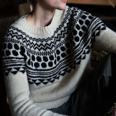 Woman wearing a patterned sweater sitting indoors. Tukubook knitting book