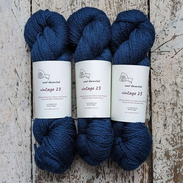 Three skeins of blue Wool Decanted vintage 23, showcasing soft 4ply Yarn on rustic wooden background.