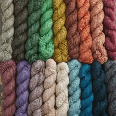 Colorful skeins of Yarnadelic Sport yarn in various shades, made from 100% Falklands Corriedale wool. Ideal for knitting and crafting.