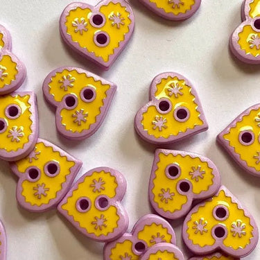 Heart-shaped buttons with yellow centers and pink borders on a white background