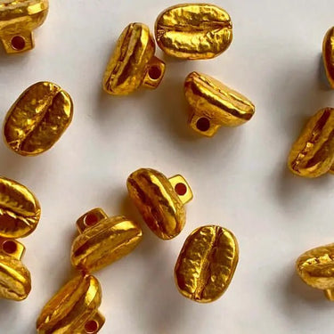 Gold-colored coffee bean-shaped beads on a white background