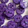 Close-up of purple buttons with a glittery finish on a white background