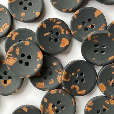 Dark gray buttons with orange speckles on a white background