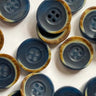 Collection of blue buttons with brownish edges on a white background