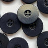 Close-up of black buttons with a central metallic button on a white background