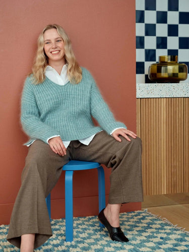 Smiling person wearing a cozy sweater, representing 52 Weeks of Sweaters knitting book pre-order promotion.