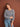 Model wearing a grey knitted sweater from 52 Weeks of Sweaters book, available for pre-order, smiling against brown background