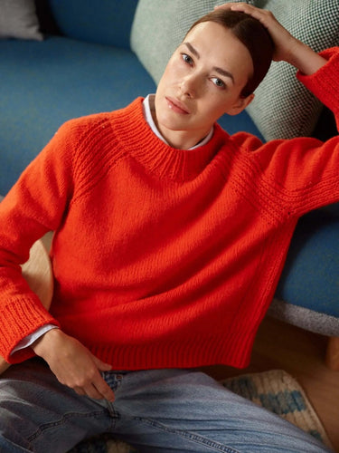 Model wearing bright red sweater from 52 Weeks of Sweaters knitting book, available for pre-order with February 2026 publication.