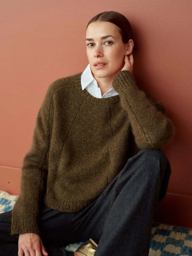 Model wearing a brown knitted sweater from the 52 Weeks of Sweaters collection, perfect for cozy winter wear in 2026. Pre-order now.
