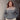 Person wearing a two-tone sweater standing against a concrete wall.