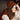Person wearing a brown knitted hat and vest in a dimly lit room.